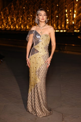celebridades mejor vestidas - Image may contain Gigi Hadid Clothing Dress Formal Wear Evening Dress Adult Person Fashion Accessories and Bracelet